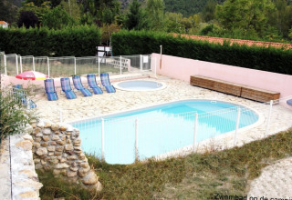 Außenpool und Kinderbecken mit Liegestühlen und Sonnenschirm auf Camping le Rotja in Okzitanien, Frankreich.