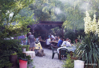 Outdoor barbecue gathering at Camping le Rotja in Occitanie, France, with guests enjoying food and company.