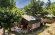 Tende safari al Camping le Rotja in Occitania, Francia, circondate da alberi e montagne sullo sfondo.