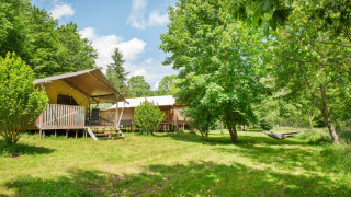 Zonnige safaritenten en hangmat in het groen bij Camping Pittoresque, vakantiedorp in Occitanië, Frankrijk.