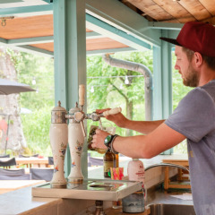 Hombre sirviendo cerveza de barril en el bar exterior del Camping Pittoresque en Occitania, Francia.