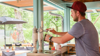 Hombre sirviendo cerveza de barril en el bar exterior del Camping Pittoresque en Occitania, Francia.