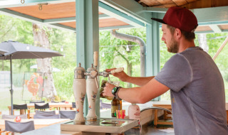 Hombre sirviendo cerveza de barril en el bar exterior del Camping Pittoresque en Occitania, Francia.