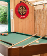 Zona de juegos al aire libre en Camping Pittoresque, Occitania, Francia, con mesa de billar y diana de dardos.