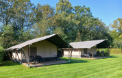 Safari tents at Familiepark de Vechtvallei in the Netherlands, set on green grass with trees in the background.