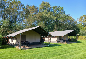 Safari tents at Familiepark de Vechtvallei in the Netherlands, set on green grass with trees in the background.