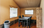 Interno di una tenda safari con tavolo da pranzo, sedie di plastica e pavimento in legno al Familiepark de Vechtvallei, Paesi Bassi.