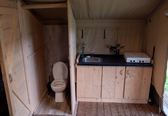 Interno di tenda safari con bagno al Camping Emmen nei Paesi Bassi, dotata di cucina e toilette.