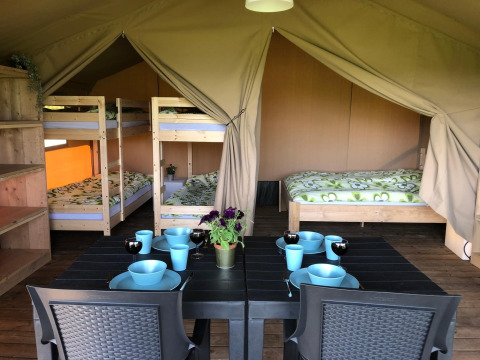 Interno di una tenda safari al Camping Emmen nei Paesi Bassi con letti a castello, matrimoniale e tavolo.