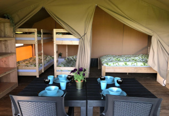 Interno di una tenda safari al Camping Emmen nei Paesi Bassi con letti a castello, matrimoniale e tavolo.