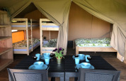 Intérieur d’une tente safari au Camping Emmen aux Pays-Bas avec lits superposés, lit double et table.