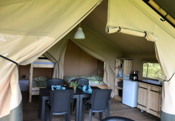 Safaritent bij Camping Emmen in Nederland met eettafel, keuken, stapelbed en tweepersoonsbed.