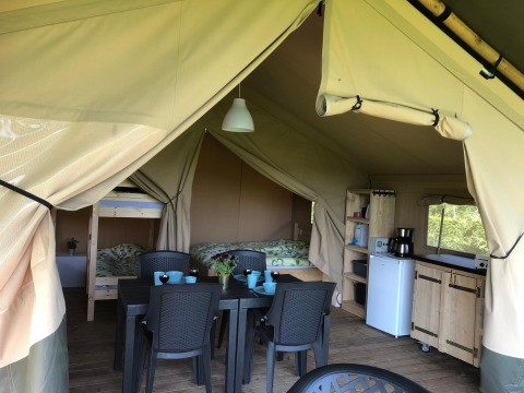 Safari tent at Camping Emmen in the Netherlands featuring dining table, kitchenette, bunk and double bed.
