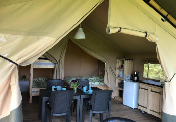 Safari-telt på Camping Emmen i Holland med spisebord, køkken, køjeseng og dobbeltseng indendørs.