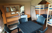 Interno di una tenda safari al Camping Emmen nei Paesi Bassi con letti a castello, tavolo e scaffali.