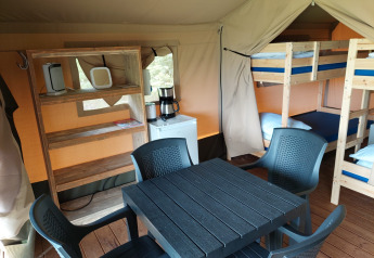 Interno di una tenda safari al Camping Emmen nei Paesi Bassi con letti a castello, tavolo e scaffali.