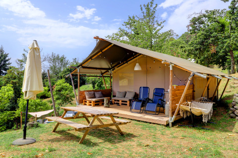 Safari-Zelt auf dem Campingplatz Pian D'Amora in Italien, mit Terrasse, Liegestühlen und Außentisch.