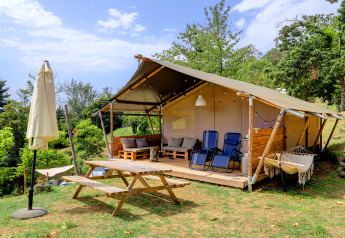 Safari-telt ved Camping Pian D'Amora i Italien med udendørs siddeområde, bord og grønne omgivelser.