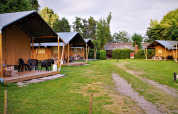 Tiendas safari con porches de madera en Camping Gorishoek, Países Bajos, rodeadas de césped verde.