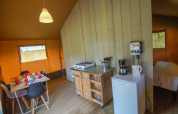 Vista interior de la tienda Safari en Camping Gorishoek, con mesa de comedor, cocina y dormitorio.