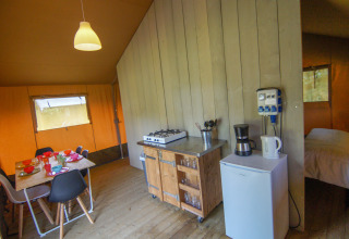 Binnenzicht van de safaritent op Camping Gorishoek, met eettafel, keuken en bed in beeld.