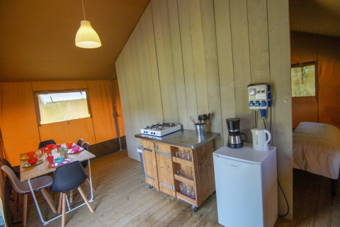 Interieur van de Safari tent bij Camping Gorishoek, met eettafel, keukenblok en slaapgedeelte zichtbaar.