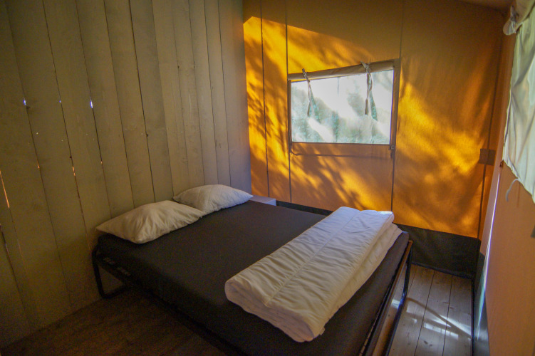Interior view of a sleeping area with double bed inside a safari tent at Camping Gorishoek, Netherlands.