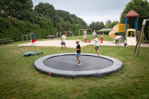 Kinderen spelen op een trampoline en speeltuin bij FarmCamps Mariekerke vakantiepark in Zeeland, Nederland.