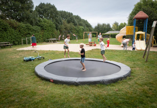 Børn leger på trampolin og legeplads i FarmCamps Mariekerke, en feriepark i Zeeland, Nederlandene.