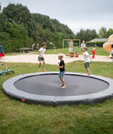 Niños juegan en una cama elástica y parque infantil en FarmCamps Mariekerke, un parque vacacional en Zeeland, Países Bajos.
