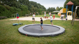 Niños juegan en una cama elástica y parque infantil en FarmCamps Mariekerke, un parque vacacional en Zeeland, Países Bajos.