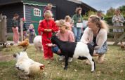 Enfants et adultes avec chèvres et poules à FarmCamps Mariekerke, parc de vacances en Zélande, Pays-Bas.