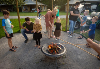 Familier og børn rister skumfiduser over bål på FarmCamps Mariekerke i Zeeland, Holland, om aftenen.