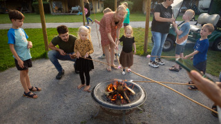 Familias y niños asan malvaviscos sobre una fogata en FarmCamps Mariekerke en Zelanda, Países Bajos.