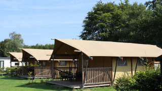 Safari tents with sanitary facilities at Familiepark de Vechtvallei in the Netherlands, green lawn.