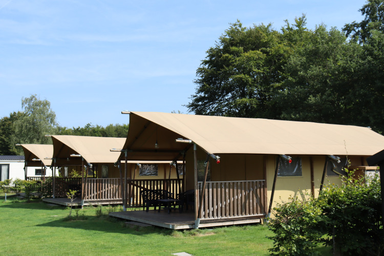 Safari tents with sanitary facilities at Familiepark de Vechtvallei in the Netherlands, green lawn.