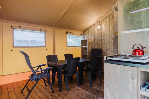 Interieur van een safaritent met eettafel, stoelen en kitchenette bij Familiepark de Vechtvallei.