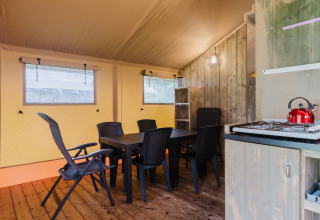 Foto del interior de una tienda safari con mesa de comedor, sillas y zona de cocina en Familiepark de Vechtvallei.