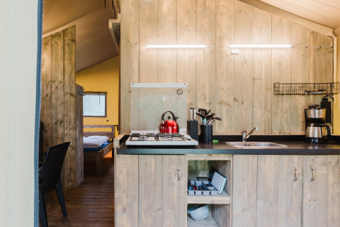 Cuisine sous tente safari avec murs en bois, cuisinière à gaz, bouilloire rouge et cafetière en Hollande.