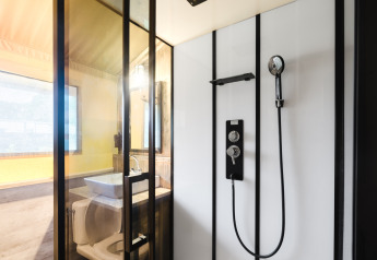 Moderne safari-teltbadeværelse med bruser, håndvask og toilet i Familiepark de Vechtvallei, Holland.