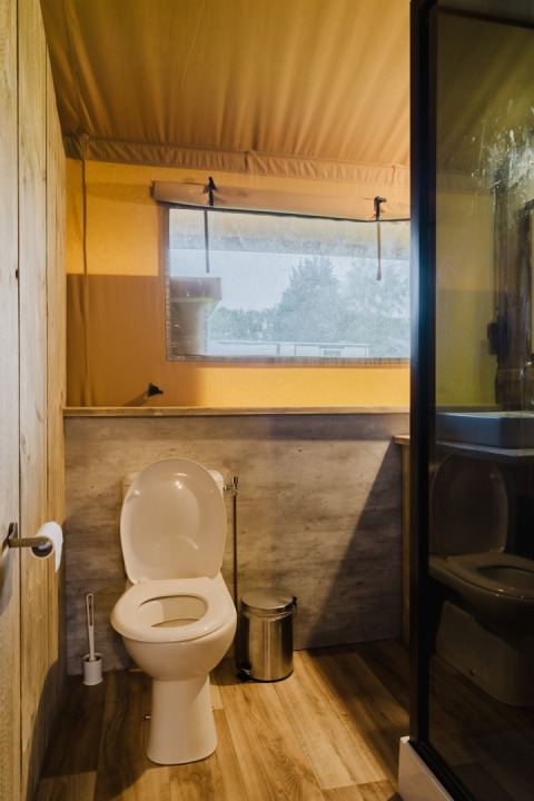 Baño con inodoro, ventana y estilo de madera en una tienda safari en Familiepark de Vechtvallei, Países Bajos.