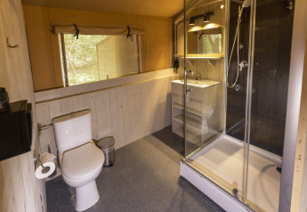 Modern bathroom in a safari tent at Camping Emmen, Netherlands, featuring shower, toilet, and sink.