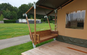Tenda safari con bagno al Camping Gorishoek nei Paesi Bassi, veranda in legno e panca a dondolo.