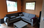 Interno della tenda Safari con bagno al Camping Gorishoek nei Paesi Bassi, con divano grigio.