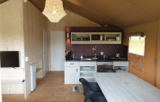 Innenansicht eines Safari-Zelts mit Holzmöbeln, kleiner Küche und Lampe bei Camping Gorishoek in den Niederlanden.