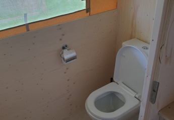 Bagno con wc in una tenda safari con pareti di legno e ampia finestra, Camping Gorishoek, Paesi Bassi.