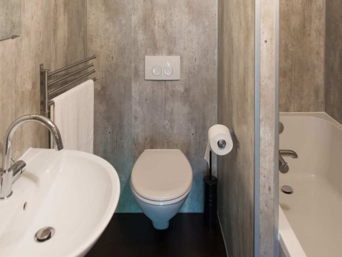 Baño en una tienda safari Barntent con inodoro, lavabo, bañera y toallero montado en la pared.