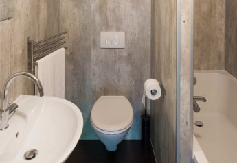 Badkamer van een Barntent safaritent met toilet, lavabo, bad, handdoekrek en toiletrolhouder aan de muur.