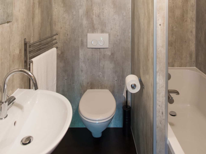 Badkamer in een safaritent Barntent met een toilet, wastafel, bad, handdoekrek en wc-rolhouder.