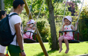 Children happily swinging with parents nearby at Camping Troisvierges, holiday park in Luxembourg.